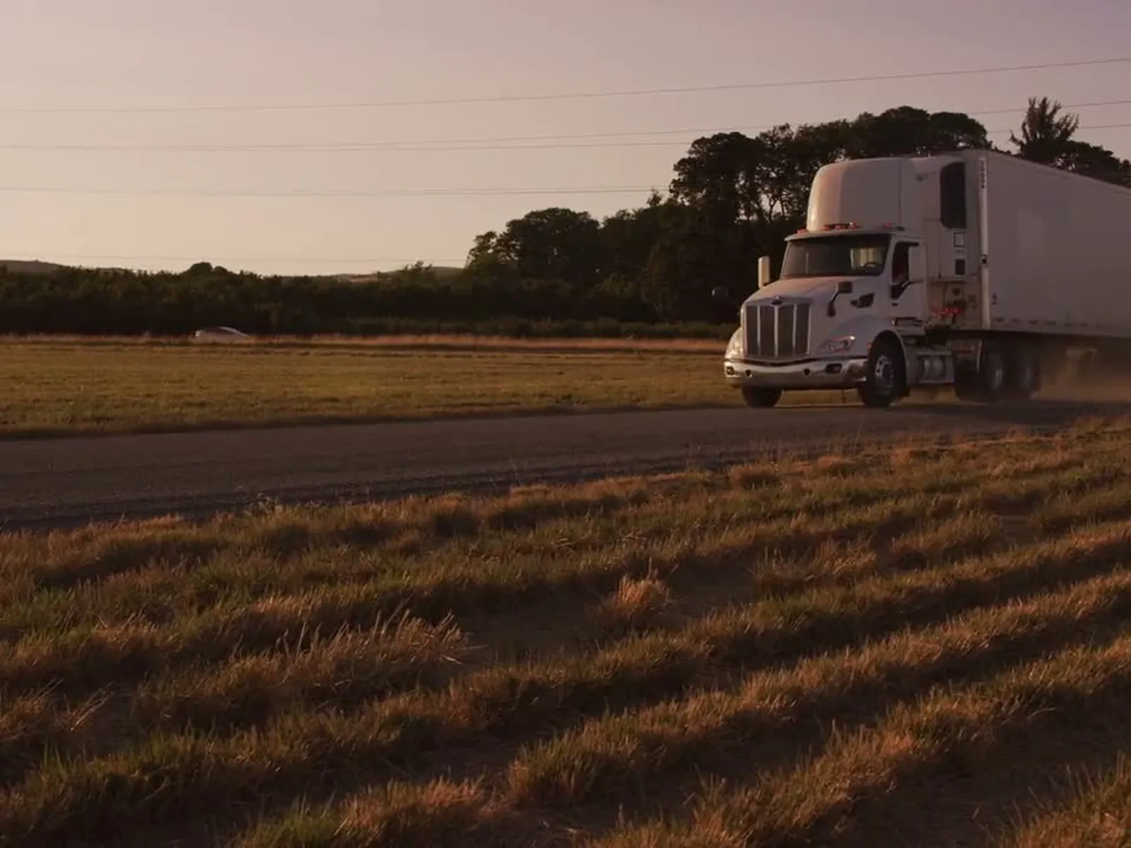 A refrigerated trailer on a country road at golden hour