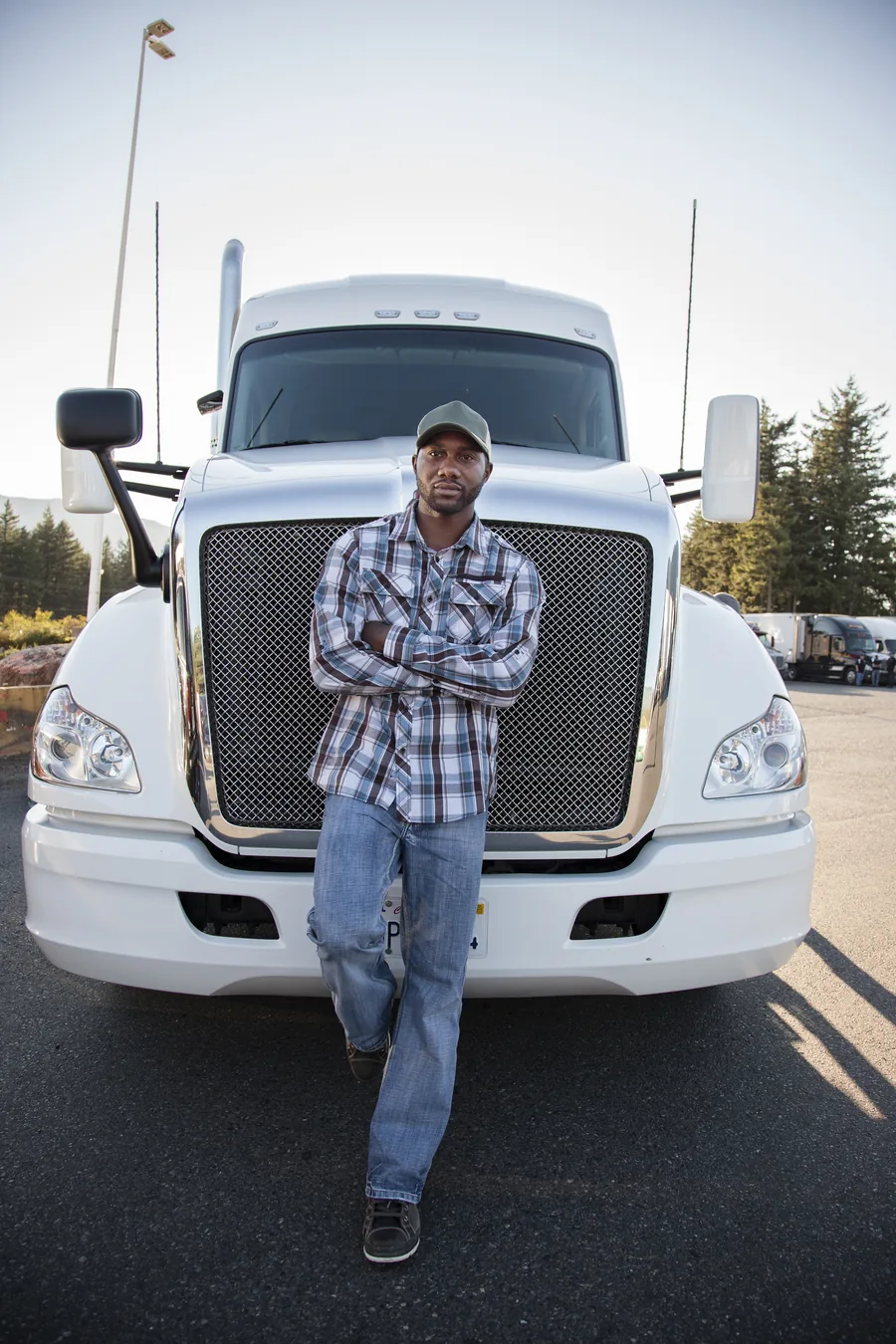 An owner-operator standing in front of his white sleeper tractor